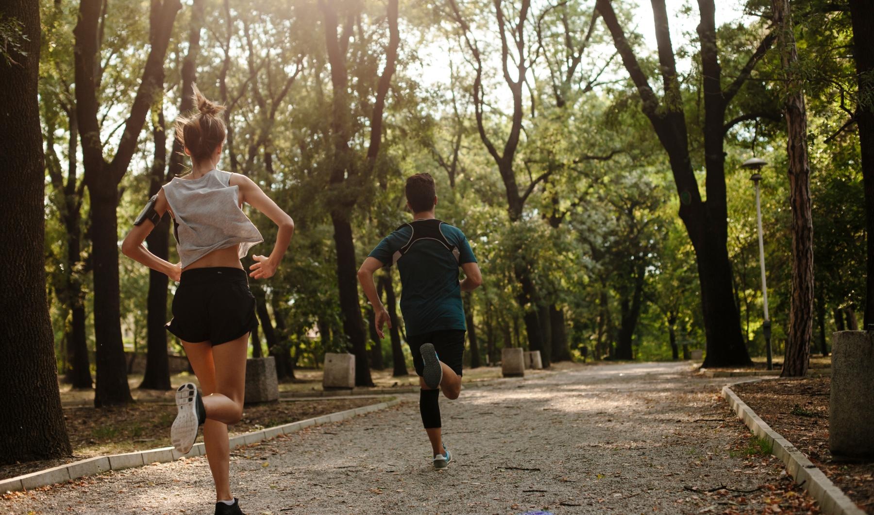 a man and woman jogging on a path in the woods