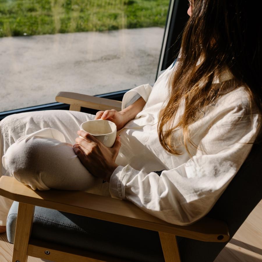 a person sitting on a chair holding a cup of coffee
